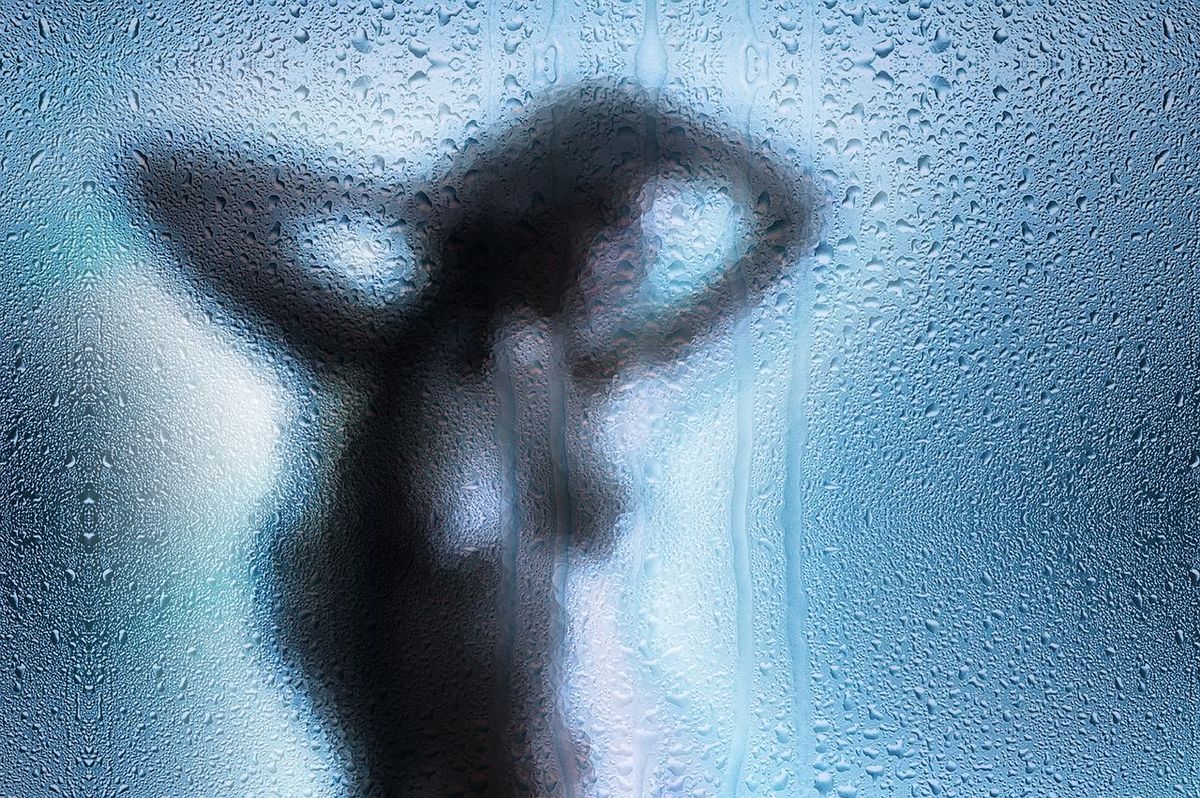 Imagen borrosa de una chica detrás de un cristal húmedo.