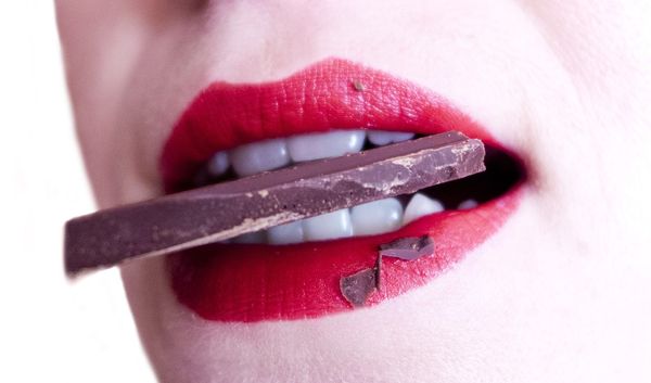 Mujer mordiendo barra de chocolate.